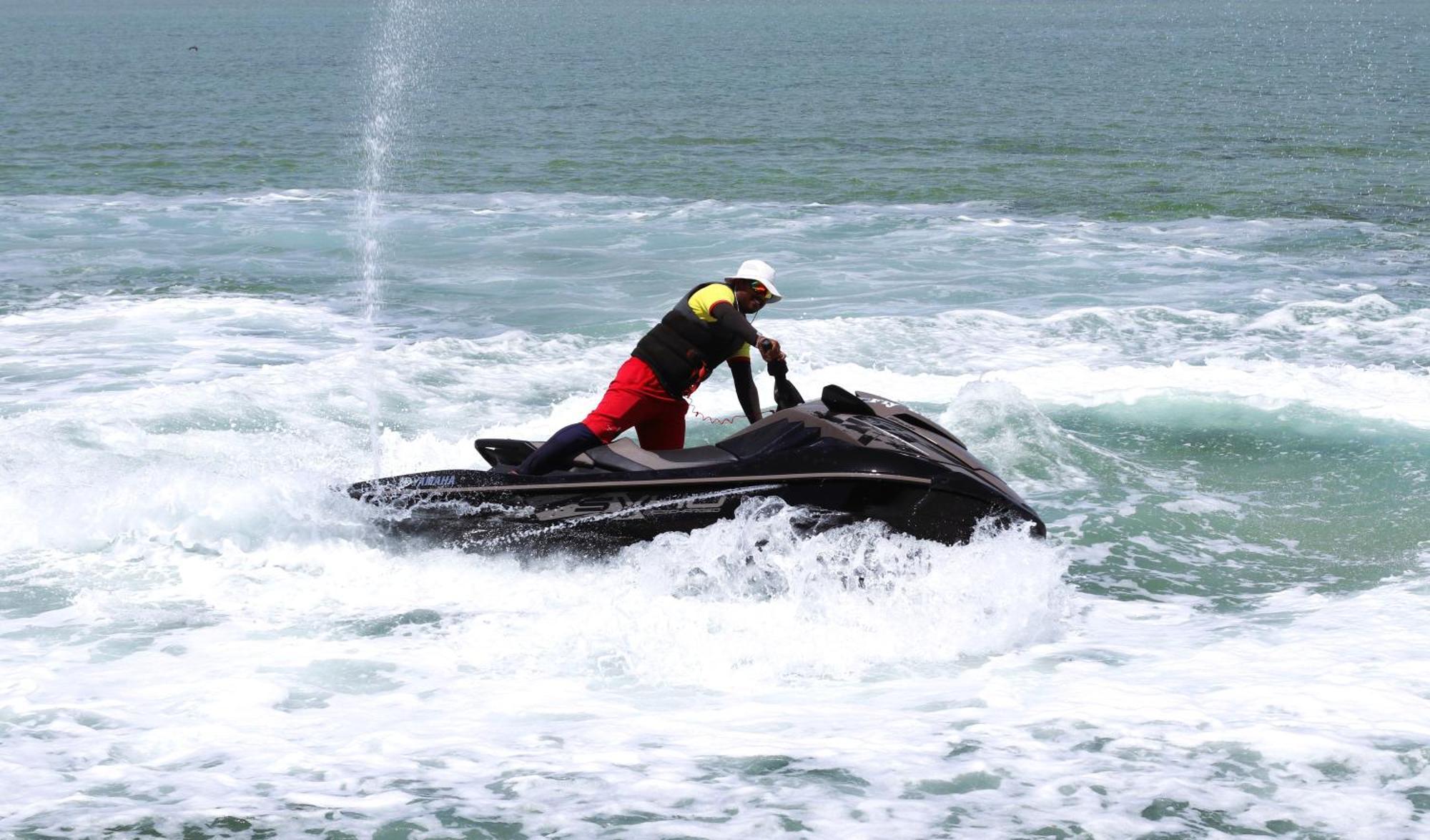 Lagoona Beach Luxury Resort And Spa Manama Exterior photo The photo shows a person riding a jet ski on the water. The rider is positioned upright, leaning forward with one hand on the handlebars, while the jet ski creates splashes of white foam around it. The water appears choppy, likely due to the motion o